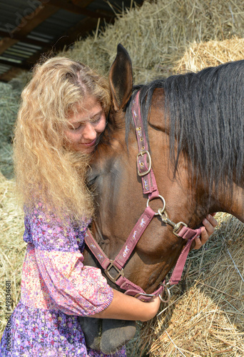 Photo: Happy Curly haired blonde girl and her horse near haystack Happy Curly haired blonde girl and her horse near haystack