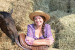 Girl and her horse resting near a haystack