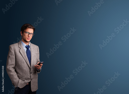 Photo: Young man standing and typing on her phone with copy space Young man standing and typing on her phone with copy space