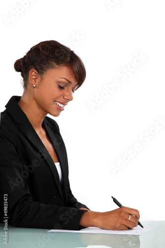 Photo: Woman sat at desk writing Woman sat at desk writing