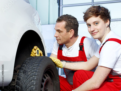 Photo: Mechanics and trainee check the tread pattern of a tire Mechanics and trainee check the tread pattern of a tire