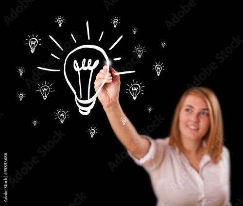 Photo: Woman drawing light bulb on whiteboard Woman drawing light bulb on whiteboard