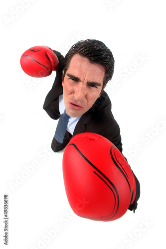Photo: businessman holding boxing gloves looking ferocious businessman holding boxing gloves looking ferocious