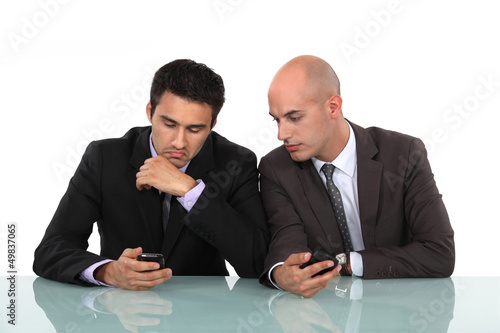 Photo: Businessmen comparing phones Businessmen comparing phones