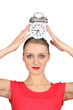 Smiling woman  putting alarm clock on her head