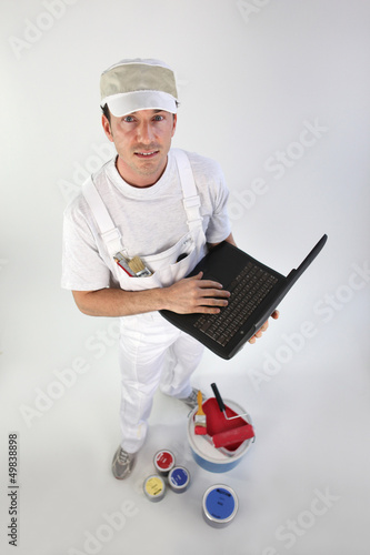 Photo: High-angle shot of a painter using his laptop High-angle shot of a painter using his laptop