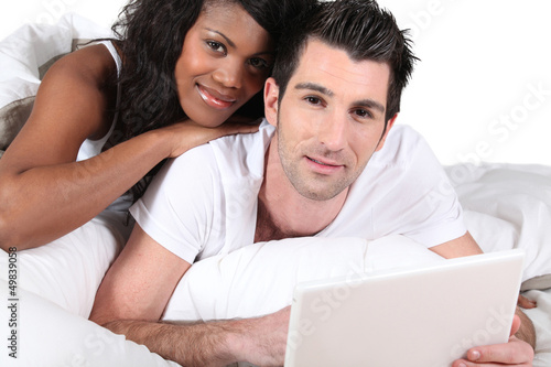 Photo: Mixed-race couple using laptop at home Mixed-race couple using laptop at home