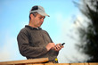 Carpenter sending text message whilst working outdoors
