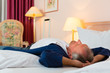 Älterer Mann liegt auf dem Bett im Hotelzimmer