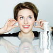 Photo: Beautiful girl puts silver coins as a pair of earrings Beautiful girl puts silver coins as a pair of earrings
