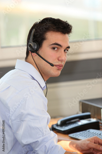 Photo: Young man wearing a headset in front of a computer Young man wearing a headset in front of a computer