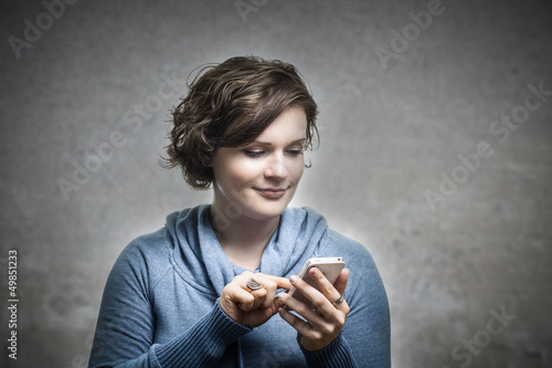 Photo: Junge Frau spielt mit ihrem Telefon rum. Junge Frau spielt mit ihrem Telefon rum.