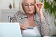 Foto: Older woman using her credit card online Older woman using her credit card online