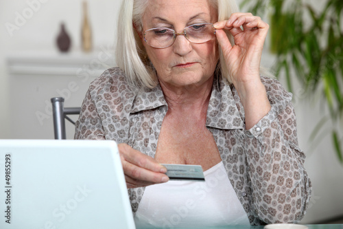 Photo: Older woman using her credit card online Older woman using her credit card online