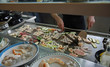 chef prepares dishes with vegetables and meat cooked on a griddl