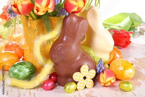 Photo: Fröhlicher Ostertisch mit Schokohasen, Ostereiern und Blumen Fröhlicher Ostertisch mit Schokohasen, Ostereiern und Blumen