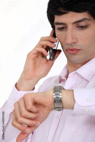 Photo: Businessman checking the time during call Businessman checking the time during call