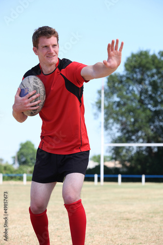 Photo: Rugby player holding the ball tight to his chest mid game Rugby player holding the ball tight to his chest mid game
