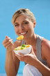 happy blond woman eating fruit salad