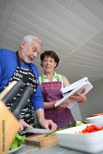 Photo: Mature couple cooking with cookbook Mature couple cooking with cookbook