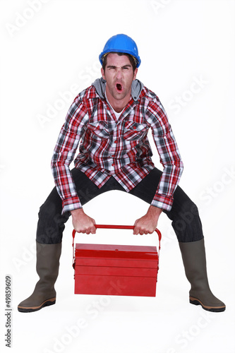 Photo: Worker struggling to lift tool box Worker struggling to lift tool box