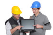 Father and son builder team pointing at laptop