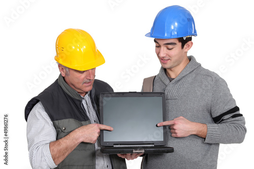 Photo: Father and son builder team pointing at laptop Father and son builder team pointing at laptop