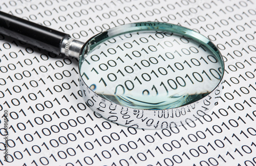 Photo: magnifying glass on a binary code magnifying glass on a binary code
