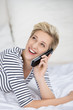 lachendes frau telefoniert auf dem bett