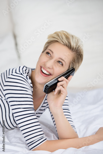 Photo: lachendes frau telefoniert auf dem bett lachendes frau telefoniert auf dem bett