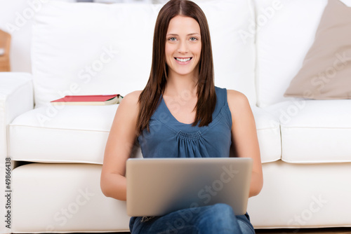 Photo: frau sitzt mit laptop vor dem sofa frau sitzt mit laptop vor dem sofa