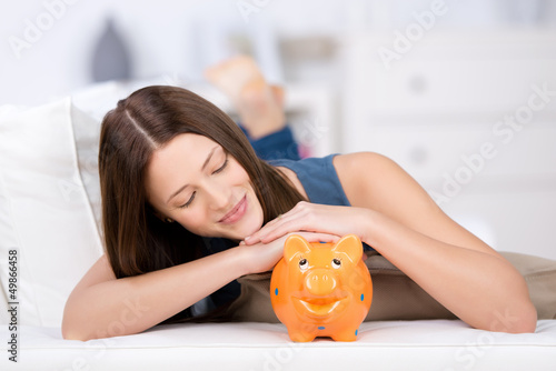Photo: frau schaut zufrieden auf ihr sparschwein frau schaut zufrieden auf ihr sparschwein