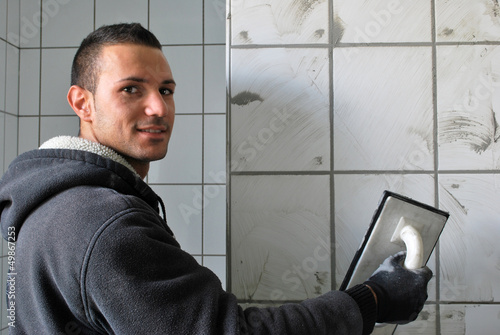 Photo: Junger freundlicher Fliesenleger bei der Arbeit Junger freundlicher Fliesenleger bei der Arbeit