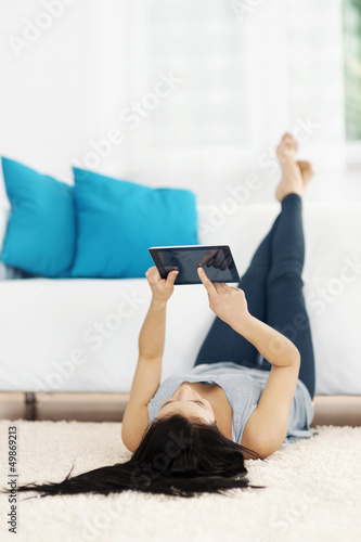 Photo: Young woman using tablet on the floor Young woman using tablet on the floor