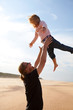 Foto: Father throwing daughter in the air at the beach Father throwing daughter in the air at the beach
