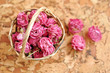 Photo: Small pick roses in a handmade straw basket on a wooden table Small pick roses in a handmade straw basket on a wooden table