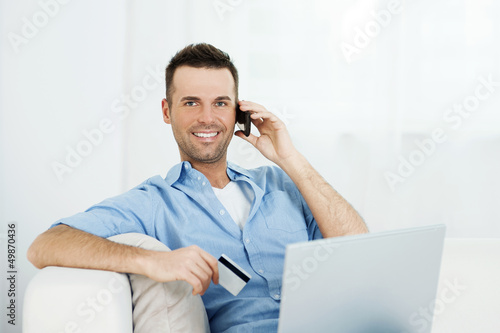 Photo: Smiling male shopping via internet. Smiling male shopping via internet.