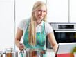 Woman in the kitchen using electronic tablet for cooking
