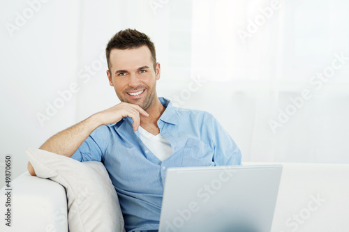 Photo: Portrait of handsome man with laptop on sofa Portrait of handsome man with laptop on sofa