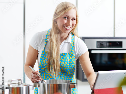 Photo: Woman in the kitchen using electronic tablet for cooking Woman in the kitchen using electronic tablet for cooking