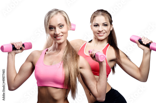 Photo: Two beautiful young woman doing fitness exercise with dumbbells Two beautiful young woman doing fitness exercise with dumbbells