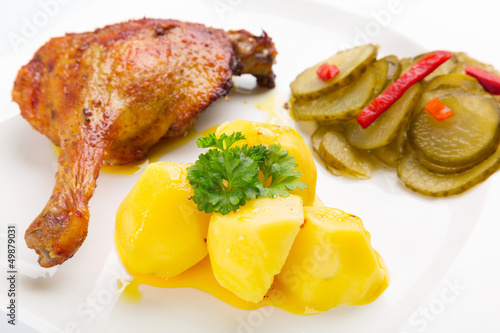 Photo: Roast duck leg with potatoes and pickes on the plate Roast duck leg with potatoes and pickes on the plate