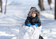 Cute boy playing with snow in the winter park