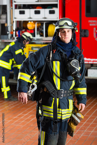 Photo: Feuerwehrmann steht in Uniform vor einer Feuerwehr Feuerwehrmann steht in Uniform vor einer Feuerwehr