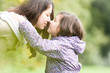 Mother and daughter looking at each other in park.