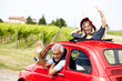 Mature couple enjoying a road trip in a small red car
