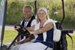 Mature couple riding in golf cart