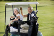 Mature couple riding in golf cart