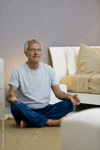 Photo: Mature man doing yoga in bedroom Mature man doing yoga in bedroom