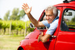 Mature man enjoying a road trip in a small red car